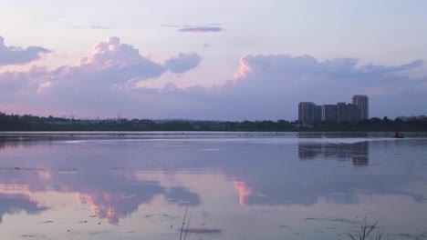 pink clouds reflection over man in boat timelapse