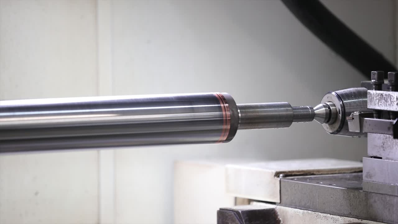 Tornio orizzontale che esegue un'operazione di tornitura di precisione su un assieme di albero metallico gradinato.