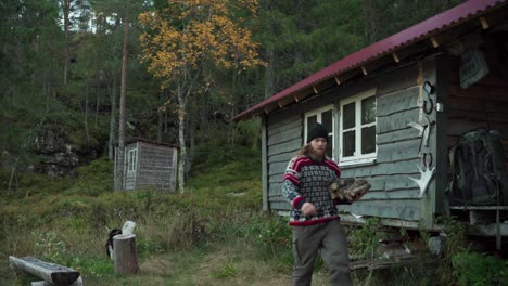 man carries firewoods outside the house in the forest