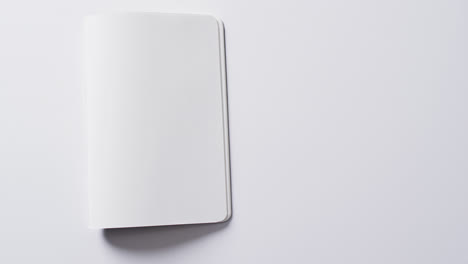 Close-up-of-open-blank-book-with-copy-space-on-white-background-in-slow-motion