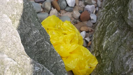 playa vieja basura basura bolsa de plástico entre piedra rocosa playa de guijarros