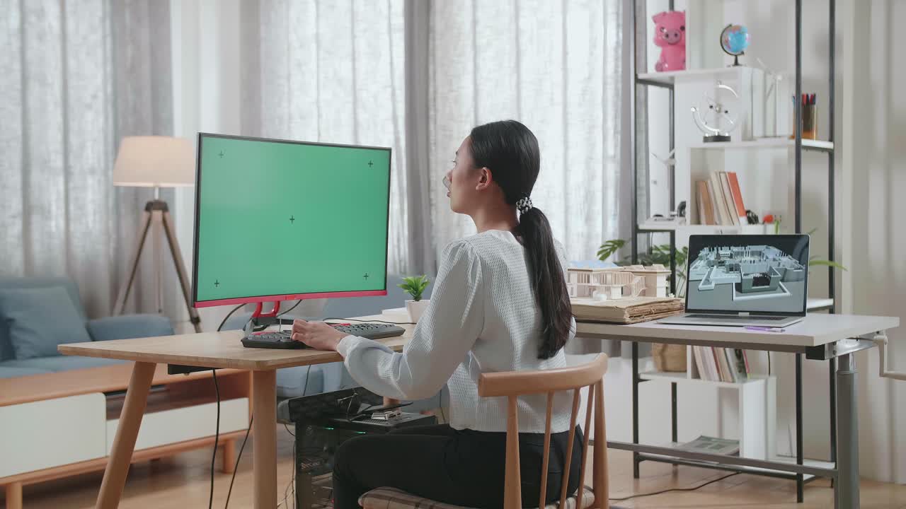 집 모델과 함께 아시아 여성 엔지니어가 집에서 모의 녹색 화면 데스크에서 일하고 있습니다.