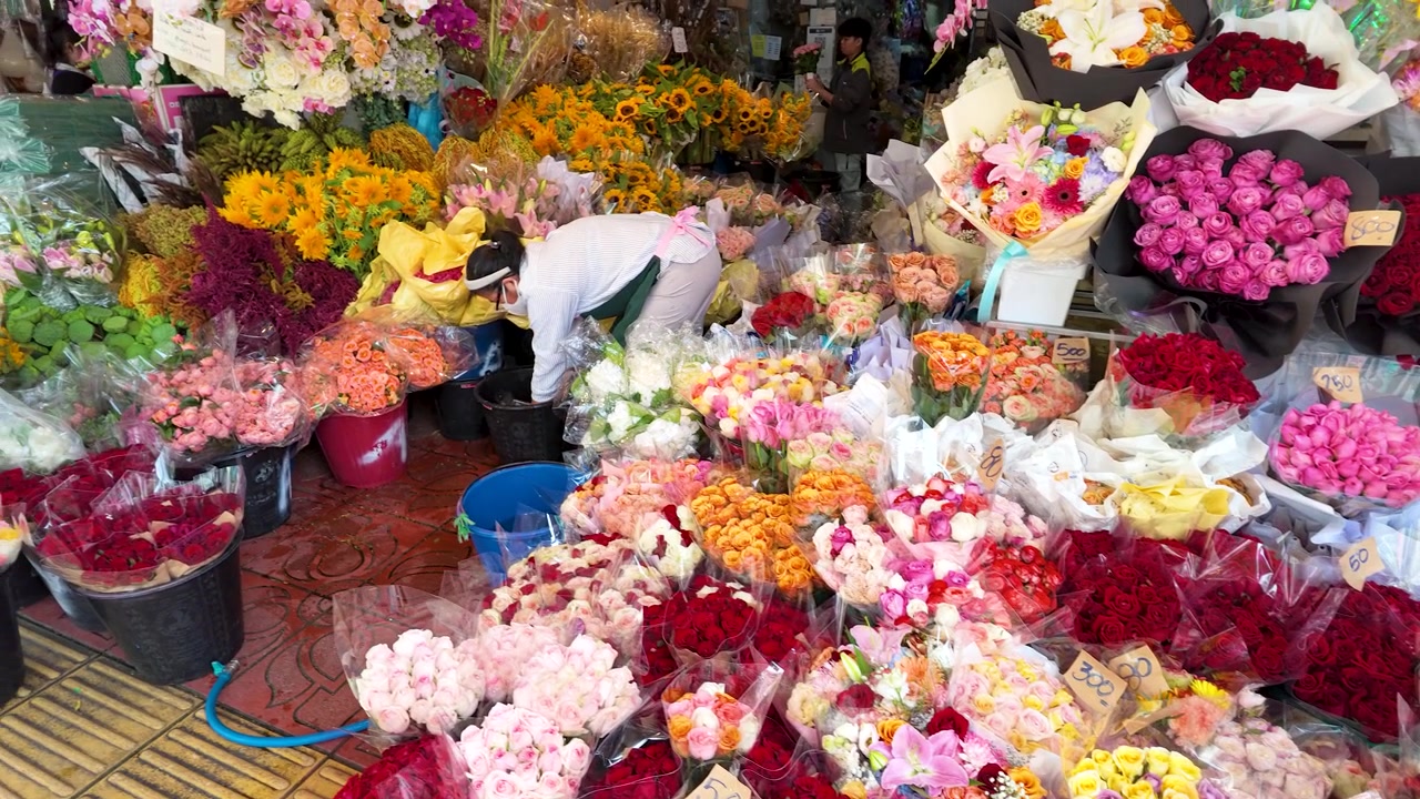 Et fugleperspektiv af en blomsterhandler, der arrangerer farverige buketter med roser og solsikker udendørs