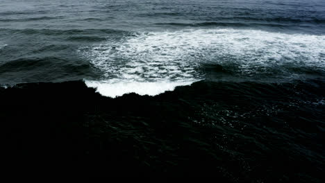 small waves roll across dark surface of pacific ocean, static aerial view