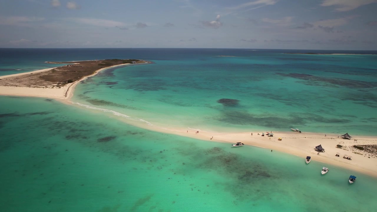 Sorvolo aereo dell'isola sabbiosa di Cayo de Agua con barche e persone sull'acqua turchese