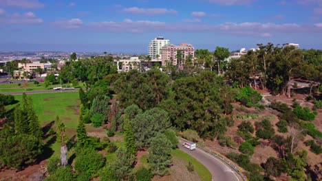 seguimiento de la vista aérea de la conducción de camiones a lo largo de la carretera de la colina en el área urbana de san diego california, calles y edificios modernos en la parte superior del parque de la colina verde, paisaje urbano del centro con horizonte