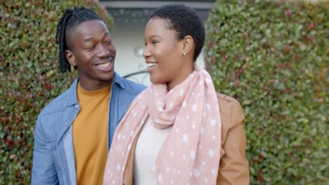 Portrait-of-happy-african-american-couple-standing-outside-house-holding-keys,-slow-motion