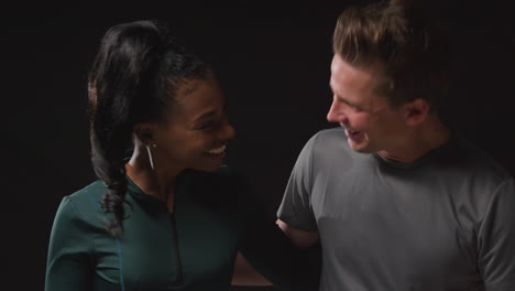 retrato de estudio de una pareja atlética sonriente o amigos en ropa de entrenamiento de fitness disparado contra un fondo negro
