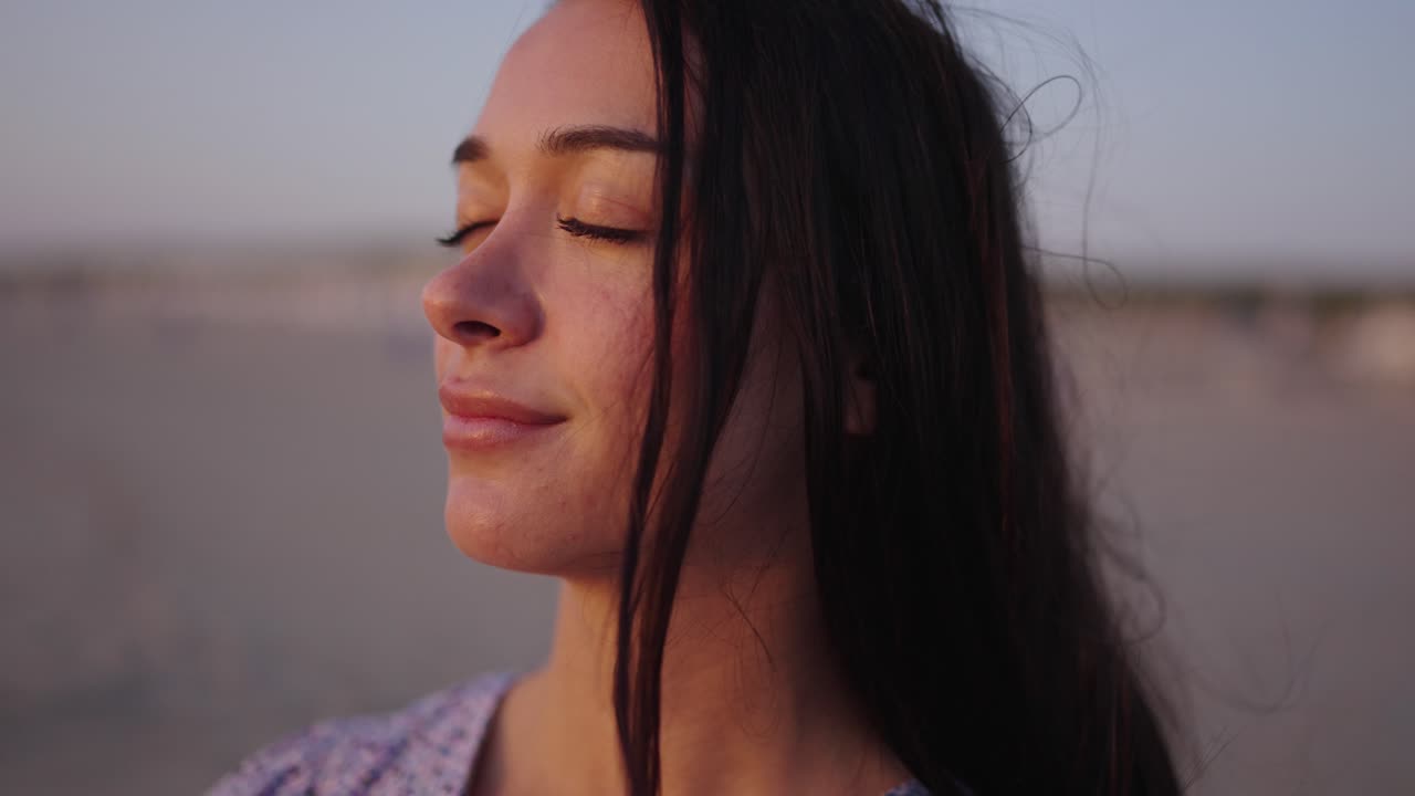 retrato de una mujer morena disfrutando de la puesta de sol dorada en la playa de los países bajos - sienta el viento y el sol - de cerca