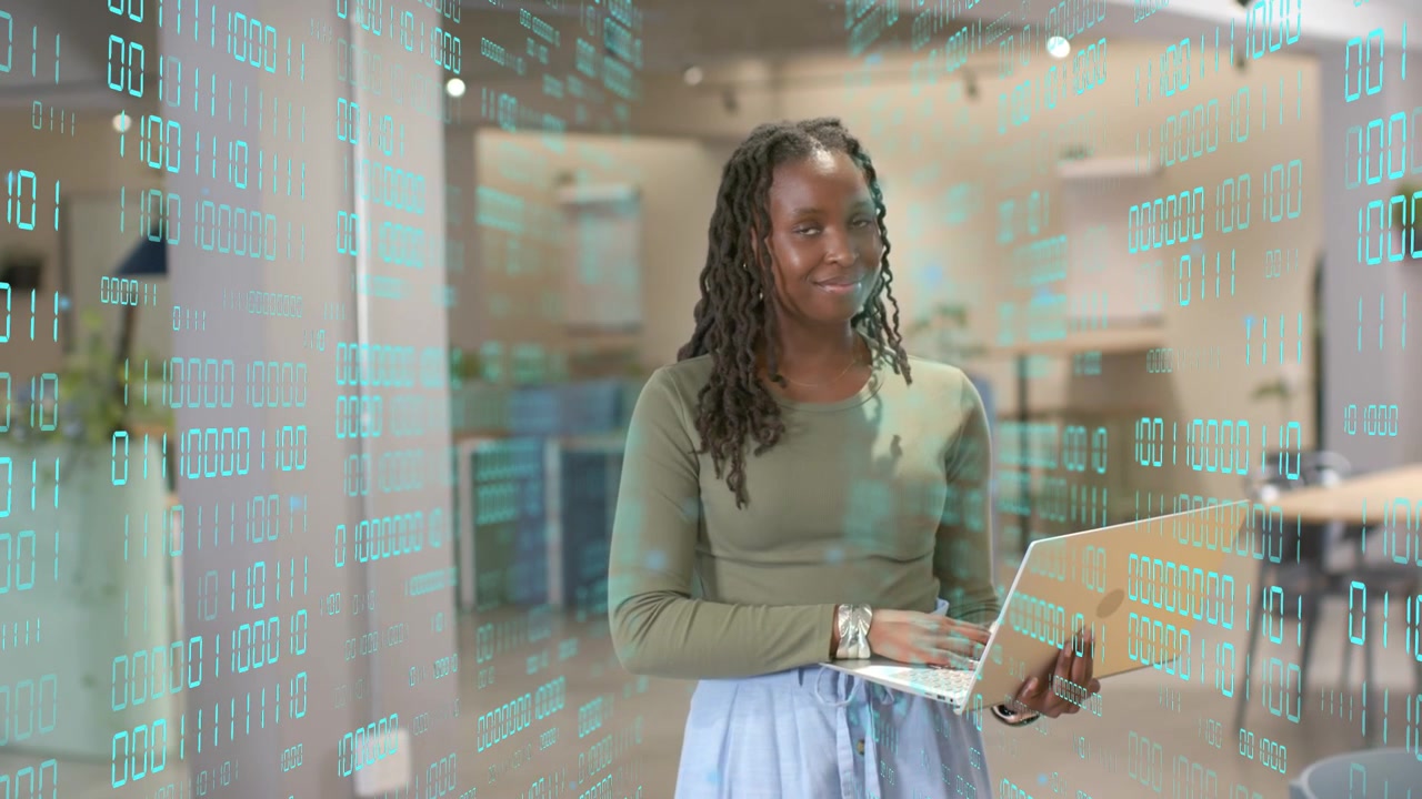 Woman holding laptop in office glancing and typing reviewing tech data with teal binary overlay