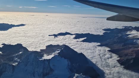 plane wing view and majestic cloudy foggy alps