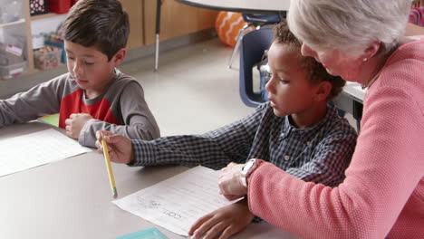 senior teacher with young schoolboys in class, side view