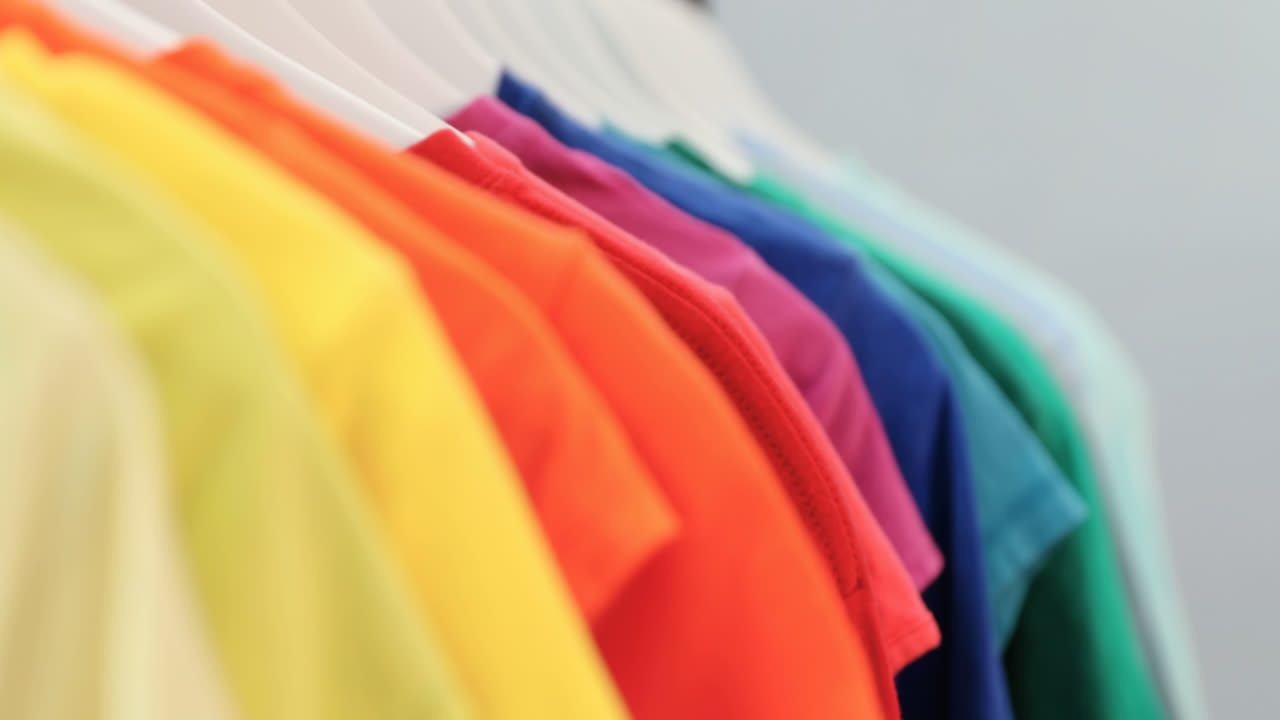 Various t-shirts arranged in a row on cloth rack 4k