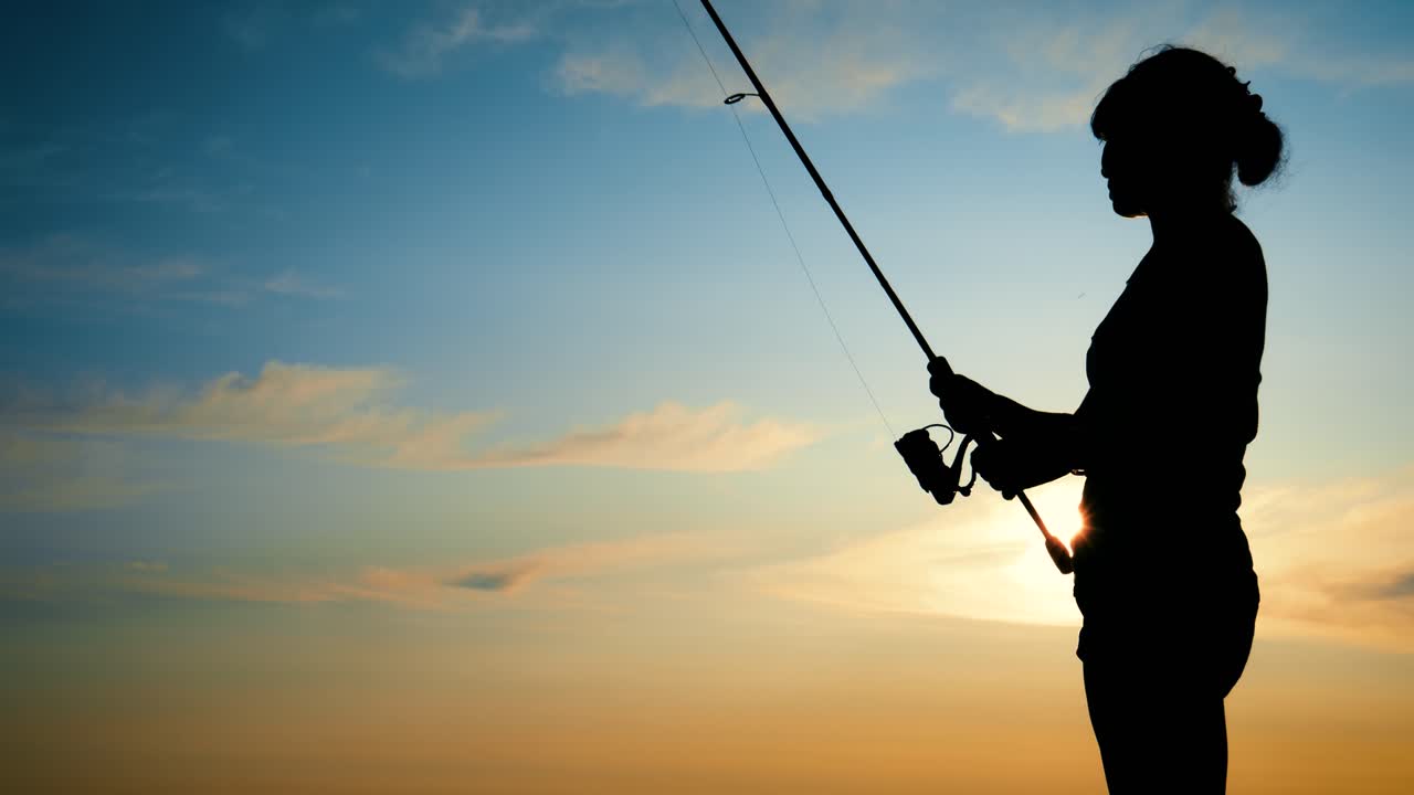 Donna che pesca con canna da spinning al tramonto