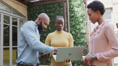 Three-african-american-male-and-female-colleagues-talking,-using-laptop-outside,-in-slow-motion