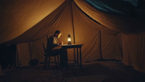 soldier writing in a tent at night