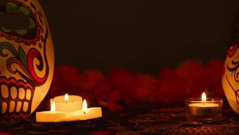 still life of decorated skull masks surrounded by candles and flowers celebrating mexican holiday of dia de muertos or day of the dead against dark background 2