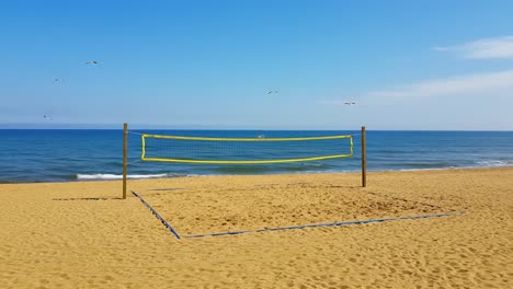 a beautiful beach volleyball court waiting for players, surrounded by serene ocean waves and a clear blue sky on a sunny day