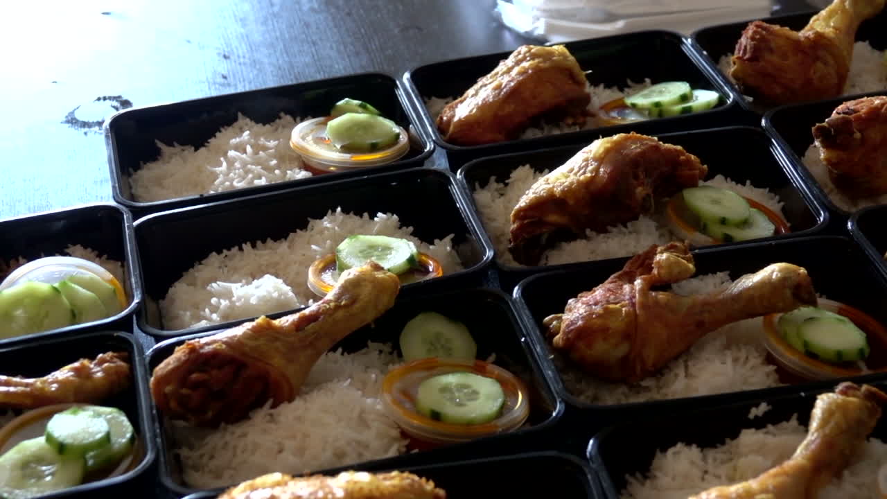 una fila de nasi lemak con pollo asado en cajas de almuerzo contenedor para fines de venta en el mercado callejero de londres