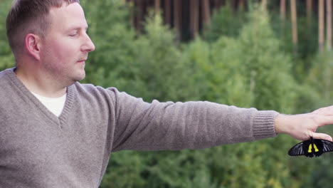 hombre observando una mariposa en un bosque