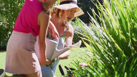 madre y hija caucásicas cuidando plantas al aire libre