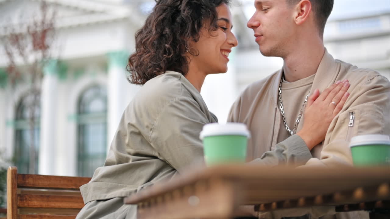 A romantic couple outdoors near a cafe. Kissing, coffee on the table. Autumn atmosphere. Slow motion