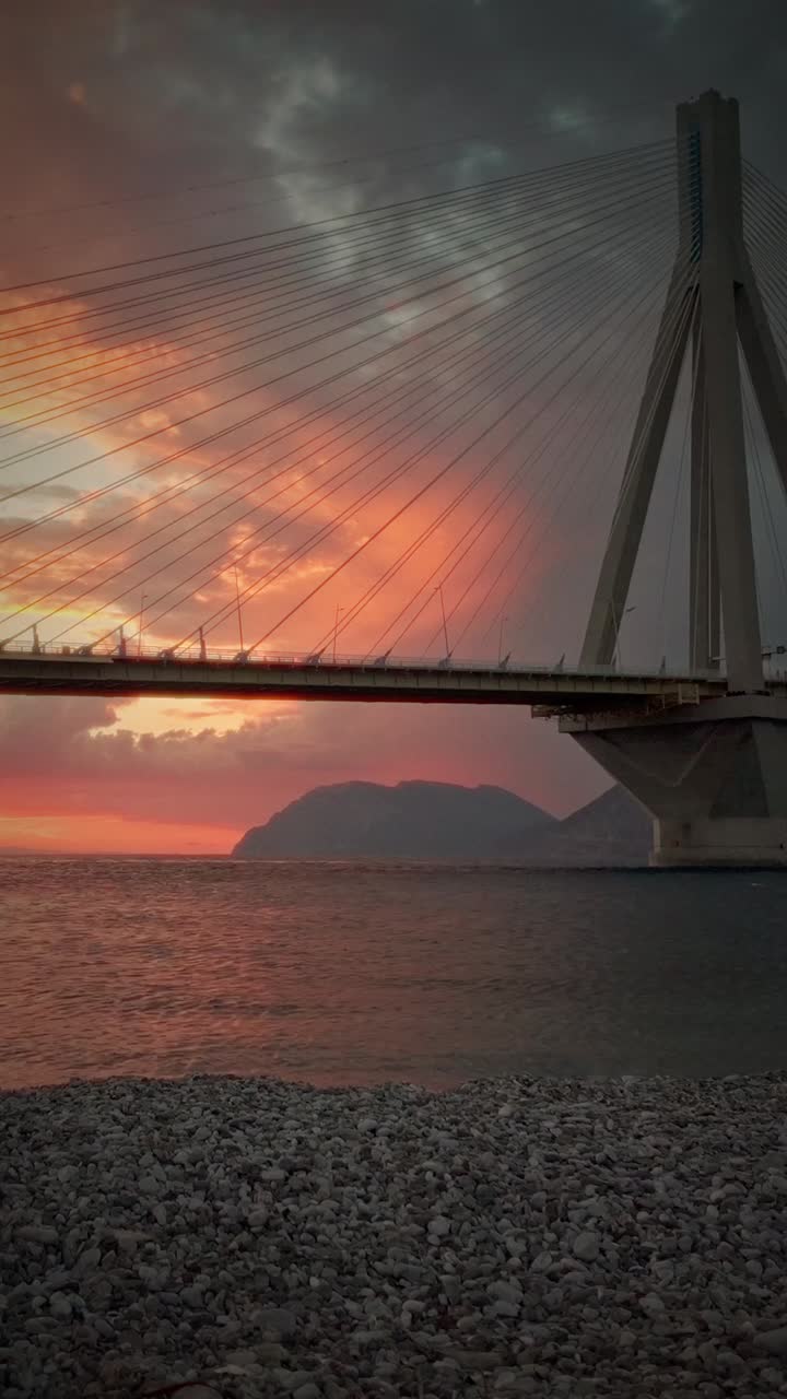Patras toll Bridge silhouette with Red sky backdrop at sunset golden hour Greece
