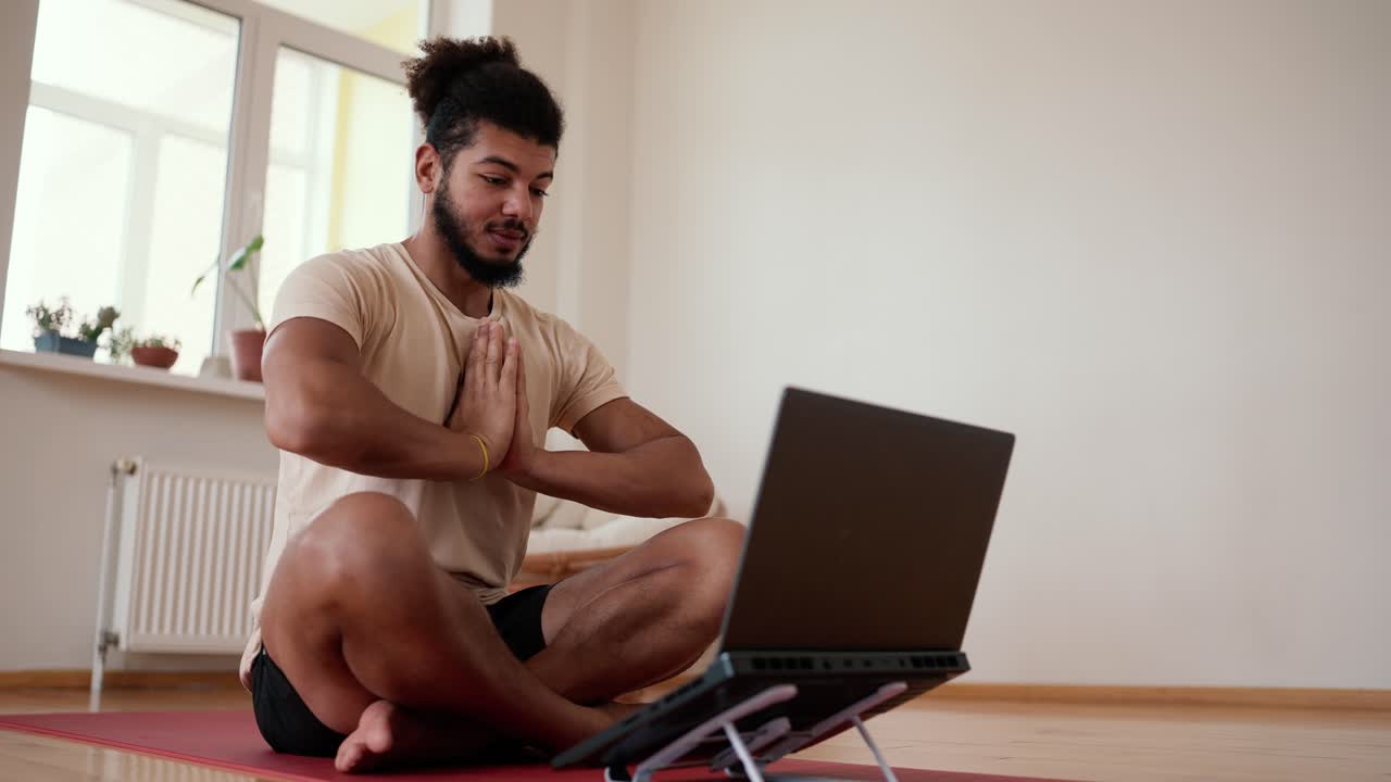 Bearded man talk on video call sit on yoga mat greets in namaste, close up