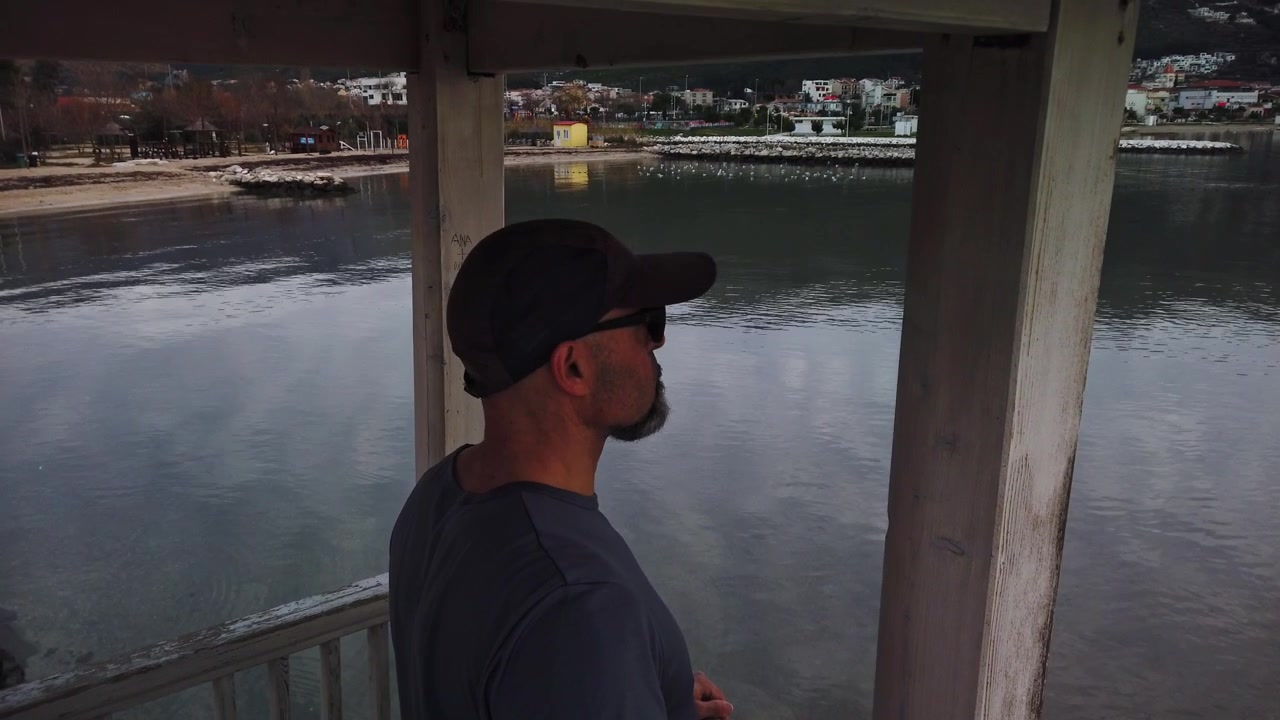Bagnino con cappellino e occhiali da sole che osserva l'acqua da una torretta di osservazione. Concetto per la sicurezza in spiaggia, la sorveglianza costiera, il servizio di salvataggio e la protezione estiva