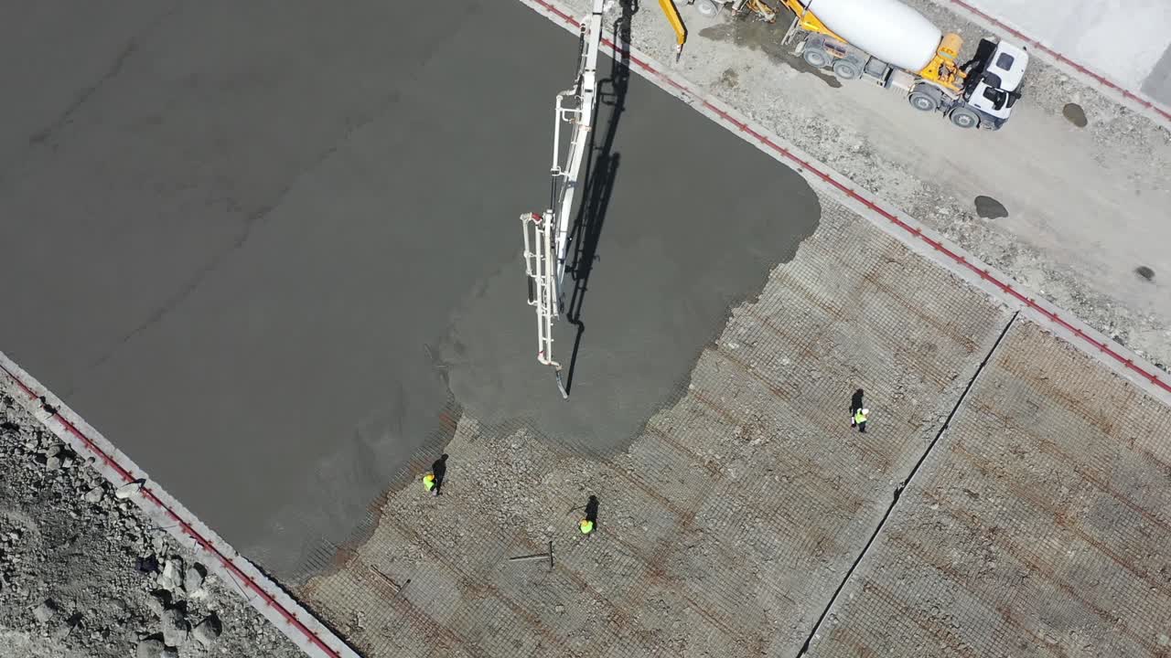 booted workers level and flatten concrete poured on the ground in construction with flat boards