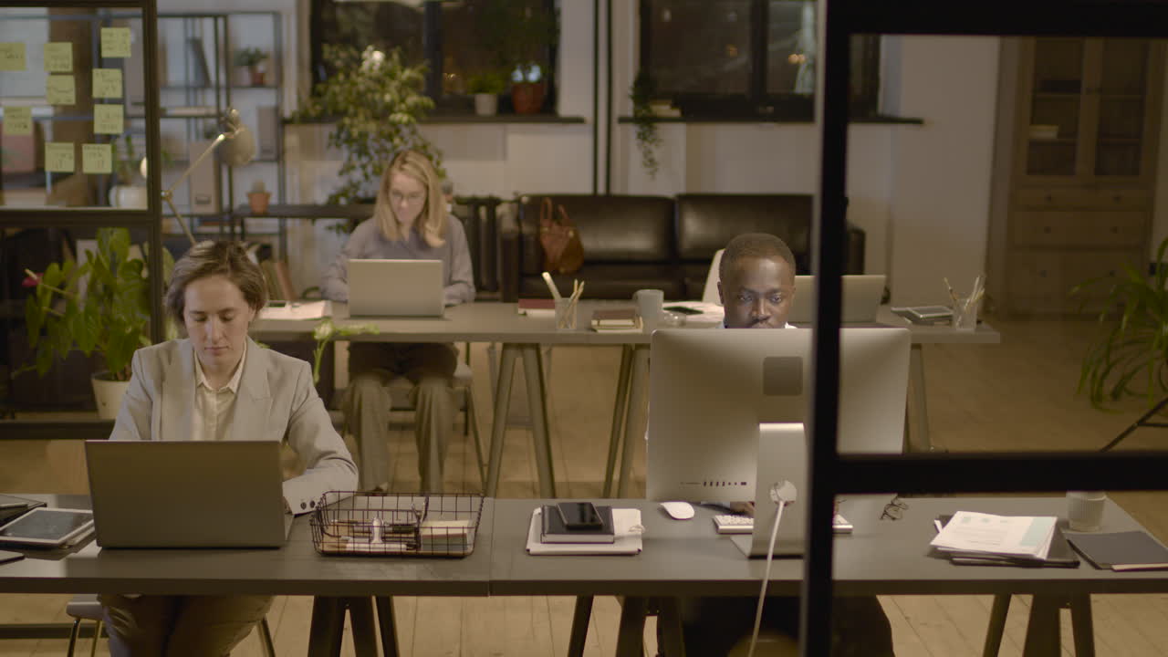 사무실 책상에 앉아 컴퓨터 작업을 하는 미국 남녀 직원