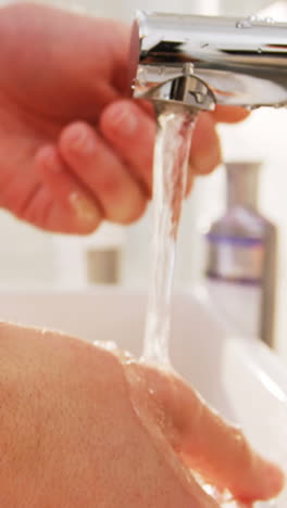 hombre lavándose las manos en el fregadero del baño