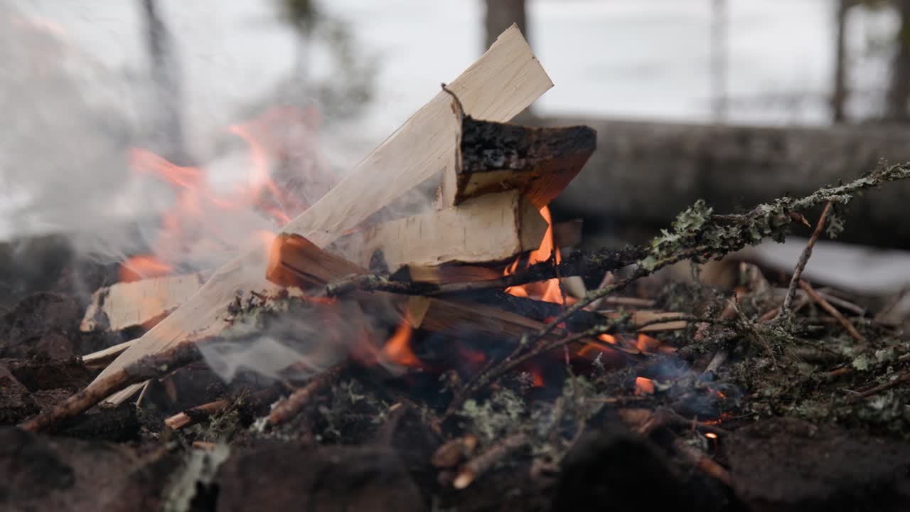Man putting firewood on campfire, slow motion, close-up