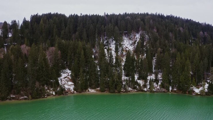 Paesaggio invernale con montagna innevata e lago turchese