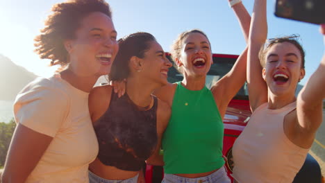 Porträt-Von-Lachenden-Freundinnen,-Die-Spaß-Daran-Haben,-Auf-Einem-Roadtrip-Vor-Dem-Auto-Für-Ein-Selfie-Zu-Posieren