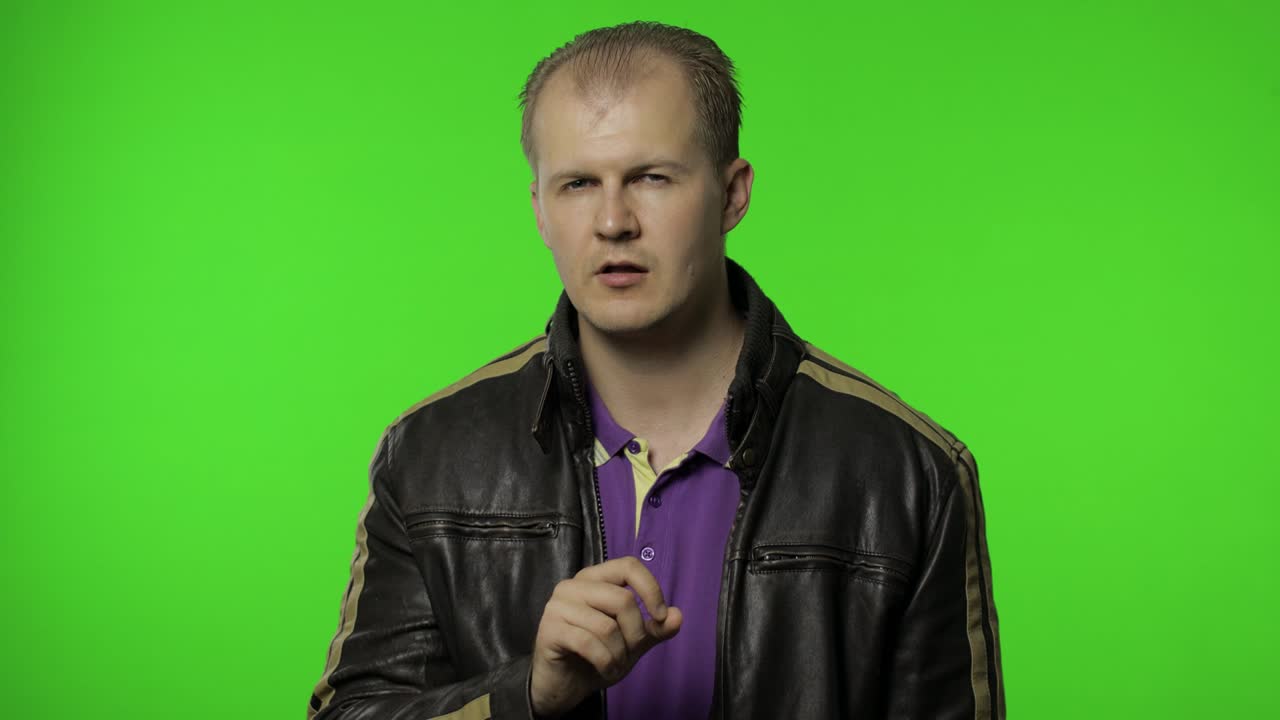 shh, no digas el secreto. rocker hombre en chaqueta marrón poniendo el dedo en los labios haciendo el gesto del silencio