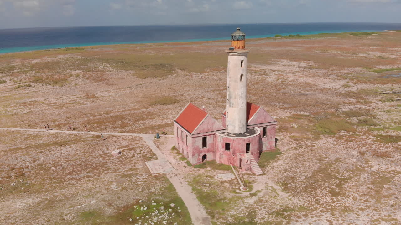 The Klein Curaçao lighthouse rises from bare coral rock, a stark landmark against blue sky. — island view