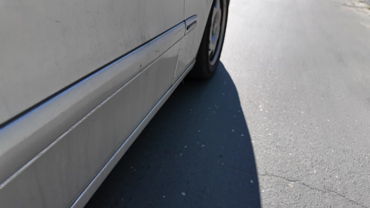 Close up of a silver car side driving down the road