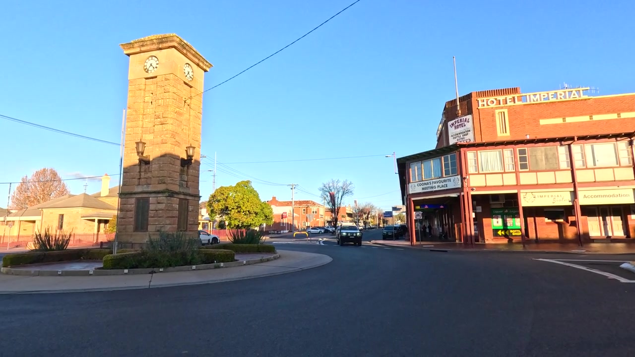 Bred panorering af et stenklokketårn og et historisk hotel i Stanthorpe, Australien.