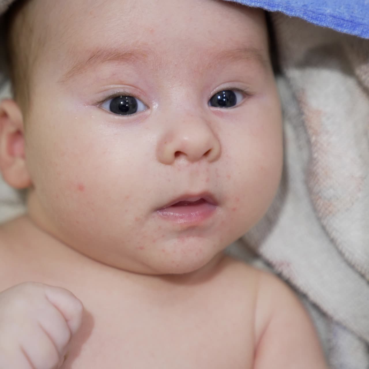 Cute child wrapped into a towel looking surprised into camera. Little kid relaxing after a bath. Close up