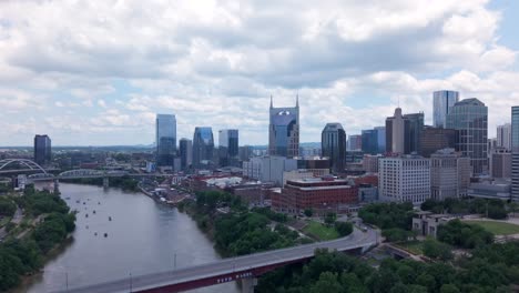 aerial view of downtown nashville rising over cumberland river under cloudy sky, tennessee, usa. rising shot