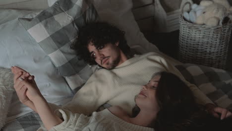 young romantic cute couple lying in bed wearing winter clothes 1