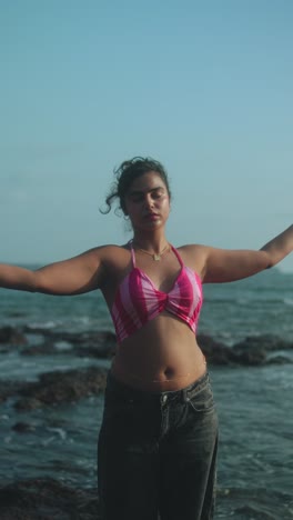 a young woman dancing on the beach, swinging a pink scarf in the breeze near the sea