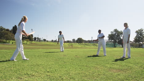playing cricket, women in white uniforms enjoying outdoor sports activity