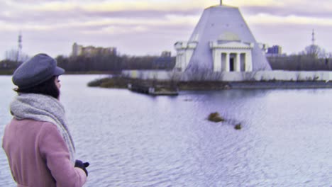 woman looking at a building on a lake in a park