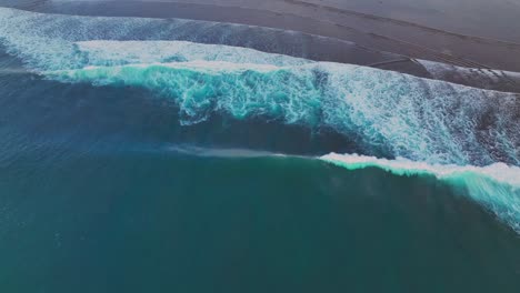 Birdseye-view-drone-clip-of-gentle-blue-waves-breaking-on-sandy-beach