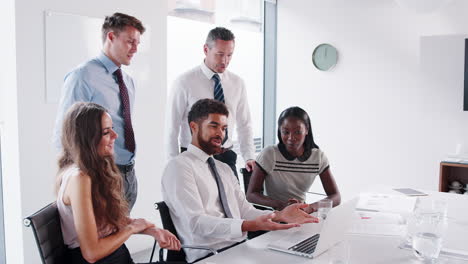 Toma-En-Cámara-Lenta-De-Hombres-Y-Mujeres-De-Negocios-Reunidos-Alrededor-De-Una-Mesa-En-Una-Moderna-Sala-De-Juntas-Trabajando-Juntos-En-Una-Computadora-Portátil