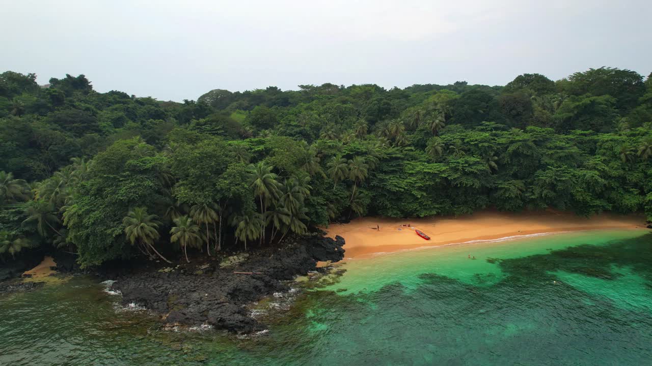 Aerial circular view of the Margarida beach with a boat anchored in the sand along with tourists at ilha do Principe (Prince Island) Sao Tome,Africa
