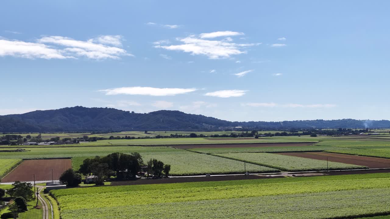 Aerial view of expansive green fields under a clear blue sky in Murwillumbah, showcasing rural landscapes and distant hills