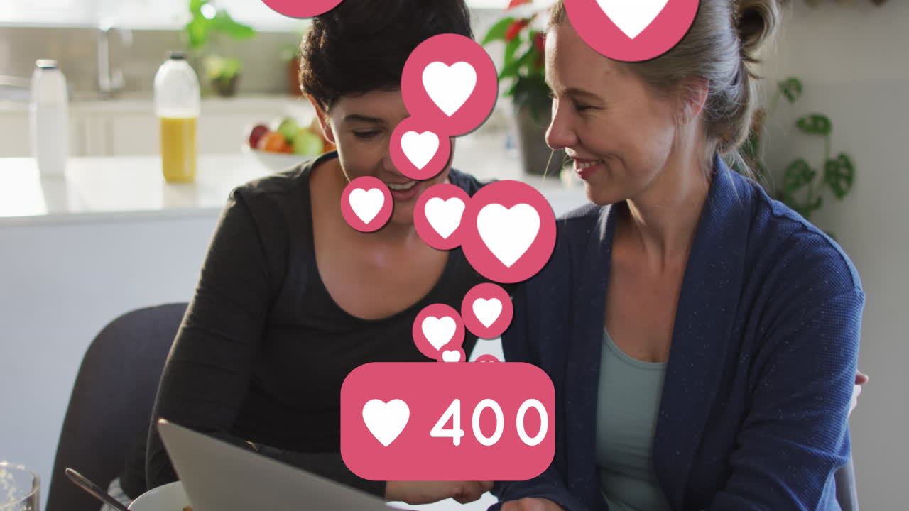 animación de emojis de corazón y números sobre una feliz pareja de mujeres caucásicas enamoradas